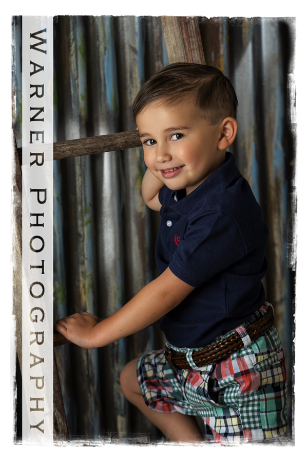 A Back to School portrait of Anson at the Warner Photography Studio next to a wooden ladder with a metal backdrop