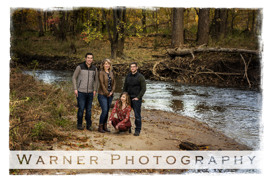 A fall family portrait on private property of the Hopkins family in the woods near a stream of water