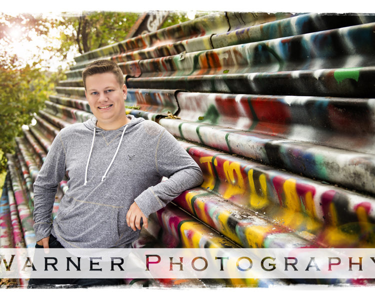 Senior portrait of Dow High School Senior Nicholas at the Bailey Bridge in Midland Michigan by the railling with graffiti