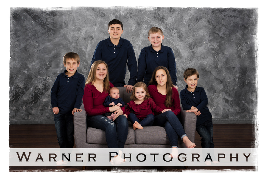 The Kreh Grandchildren at the Warner Photography Studio on a grey couch with a traditional grey background