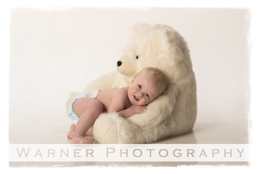 Childrens studio portrait of Amadeaus for his first birthday with a white bear and white background