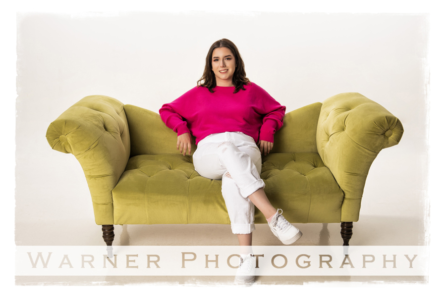 Studio portrait of Haily on a green couch at the Warner Photography Studiio