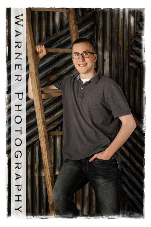 Studio portrait of Midland High School senior Josh by a ladder on a metal wall