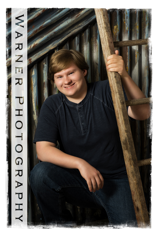 studio portrait of Hemlock High School senior Jonathan with a metal wall and a wooden ladder