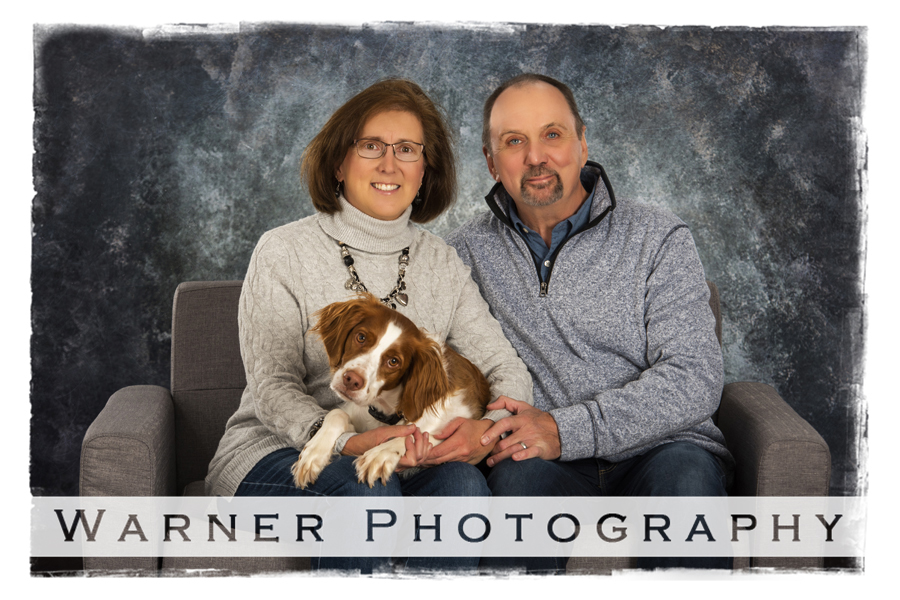 a studio portrait of the Luptowski family and their dog Trixie on a grey couch