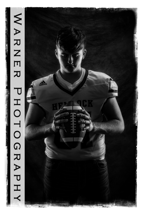 Studio portrait of Hemlock High School senior Carter in his football jersey with a football