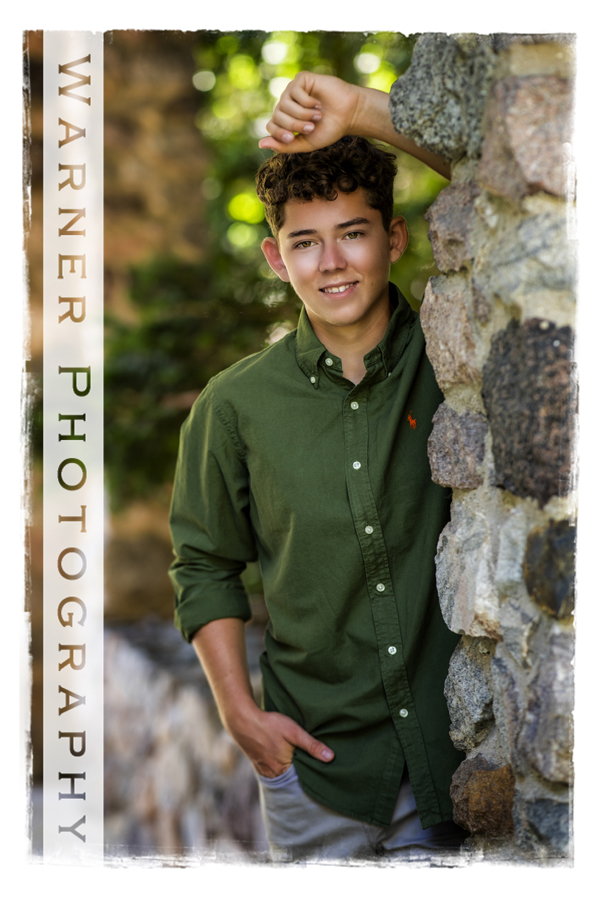 Outdoor portrait of Dow High School senior Gavin at Dow Gardens by a rock wall