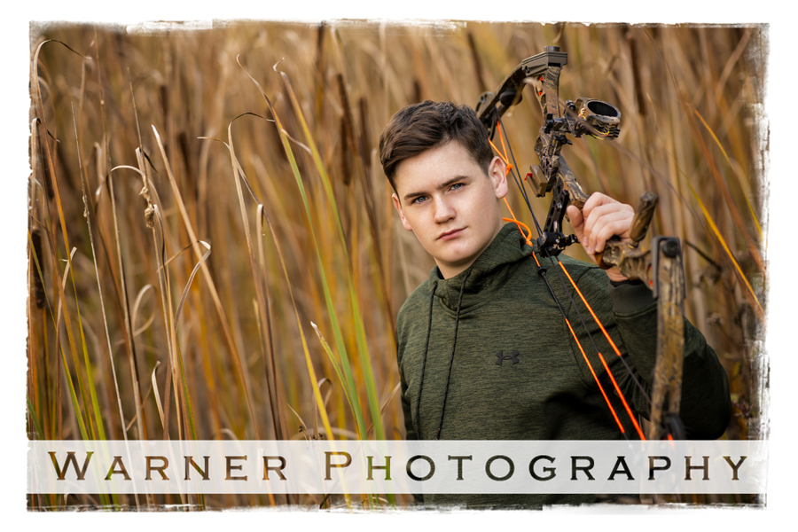 an outdoor portrait of Ogemaw Heights High School senior Cody at Chippewa Nature Center with his bow in the long grass