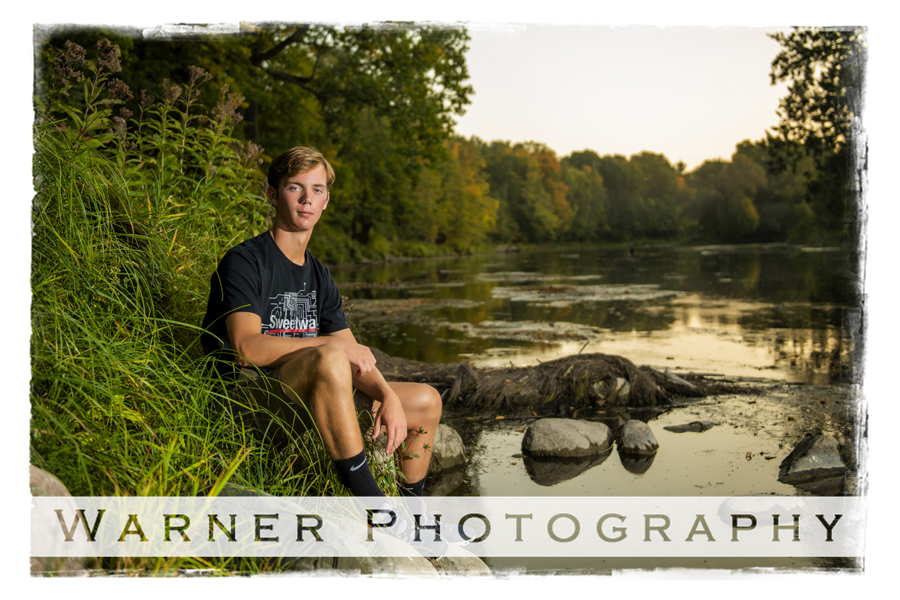 An outdoor portrait of Bullock Creek High School senior Sam at Chippewa Nature Center on the rocks by the river