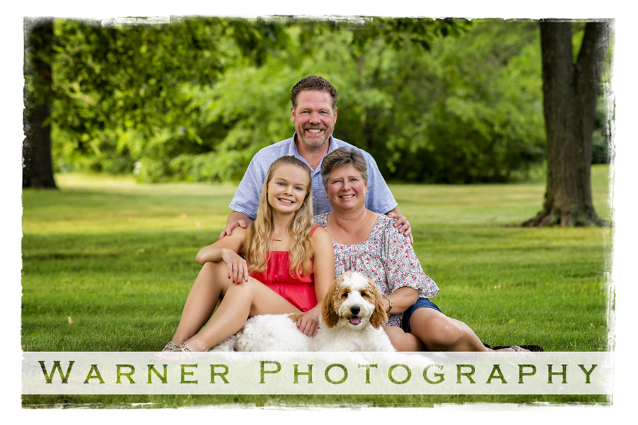 an outdoor portrait of the Welsch family at Plymouth Park with their dog