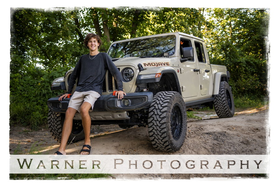 an outdoor portrait of Dow High School senior Luke with his jeep on a dirt road